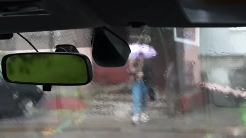 View through the windshield on a person opening an umbrella in the rain Stock Footage 195902218