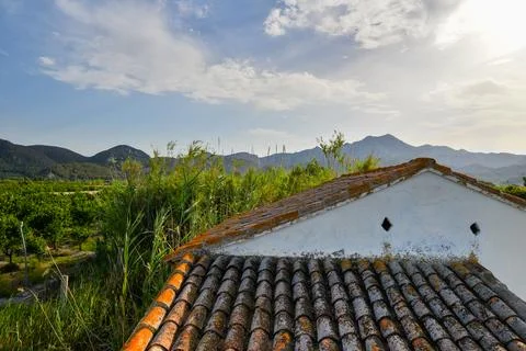 View from the tiled roof of a small white house to a mountain landscape and g Stock-Fotos