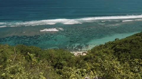View of a tiny beach and clear blue ocean from a cliff Video stock 63545648