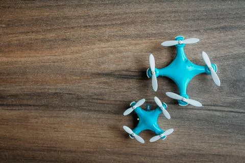 View of tiny drone on a wooden background. Small blue drone with white propel Foto stock