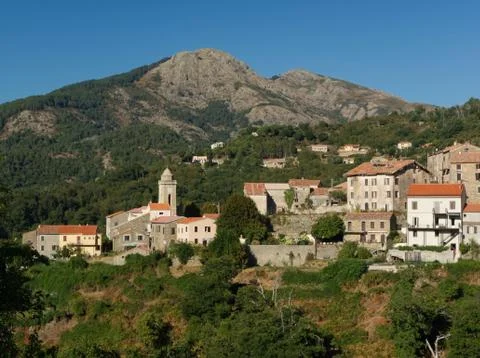 View on a tiny village with its bell tower in the mountains Stock Photos
