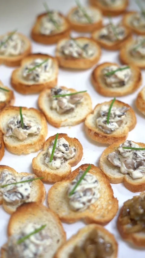 View of toasted bread bites topped with a creamy mushroom mixture and a garnish Stock Footage 321671543
