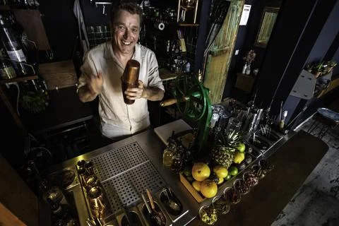 View from top of a cheerful bartender preparing a cocktail in a colourful coc Stock Photos