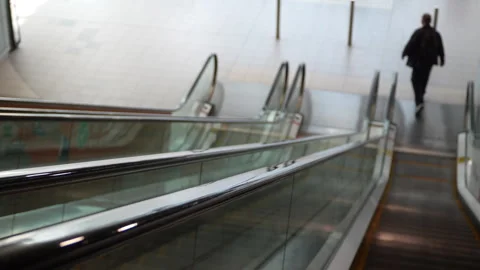 View from top of escalator as man steps off, shallow depth of field focus shift Stock Footage 332901380