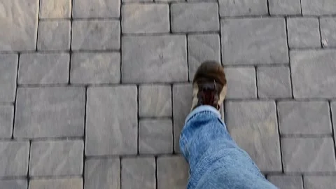 View from the top of the legs of a man walking along a grey clinker pavement. Stock Footage 143485199