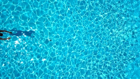 View from the top as a man dives into the pool and swims under the water Stock Footage 99720437
