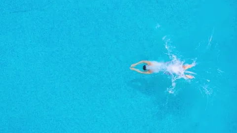 View from the top as a man dives into the pool and swims under the water. Stock Footage 133718879