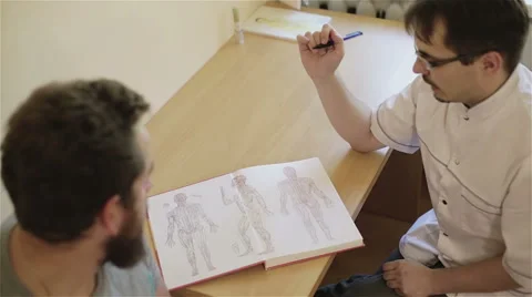 View from top. Reflexologist receives patient explaining him acupuncture points. Stock Footage 68963712