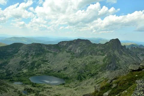 A view from the top of a ring of high mountains and a picturesque lake in t.. Stock Photos