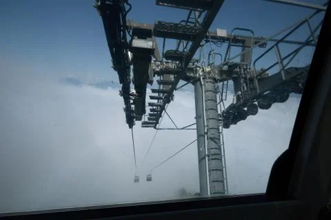 View from top of ropeway with multiple seats and stretched cables above trees in Stock Photos