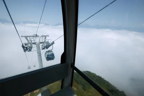 View from top of ropeway with multiple seats and stretched cables above trees in Stock Photos