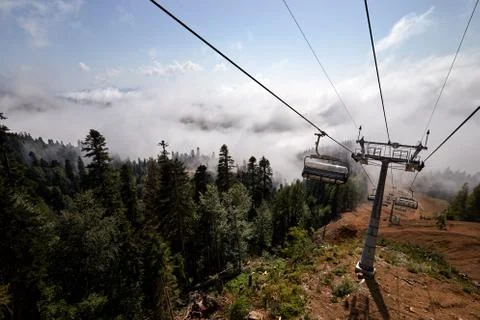 View from top of ropeway with multiple seats and stretched cables above trees in Stock Photos