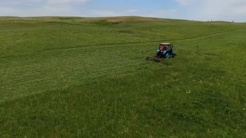 The view from the top. The tractor in the field to mow the grass. Vídeos de archivo 132719425