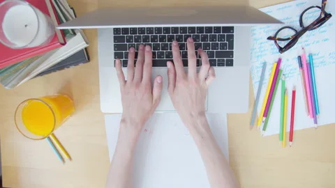 View from top women's hands typing on laptop keyboard on desk littered with Stock Footage 135815156