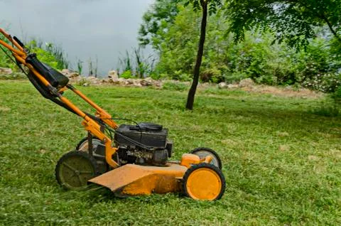 View  toward mowing machine cutting the grass in a park, residential district Stock Photos