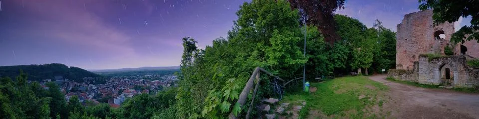 View of a town and ruins from a hillside at dusk with trees and a starry sky Stock Photos