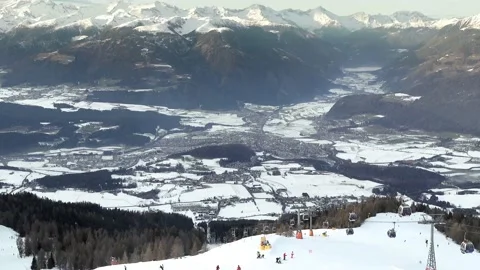 View of the town of Bruneck (Brunico) from Plan de Corones with skiers. Stock-Footage 230629205