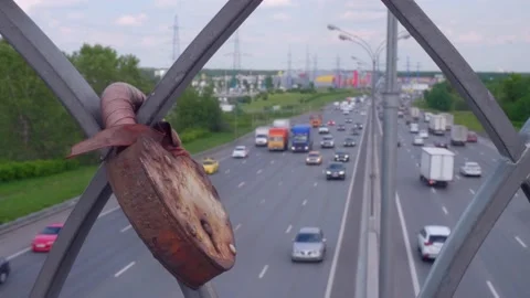 VIew of traffic on highway through rails on the bridge. Rusty lock is on the Stock Footage 133800960
