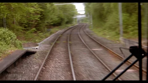 View from a train moving along curved railway tracks through a green forest Stock Footage 326369472