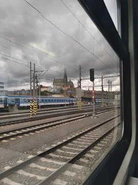 View from a train of tracks, multiple trains, and a distant church 库存照片