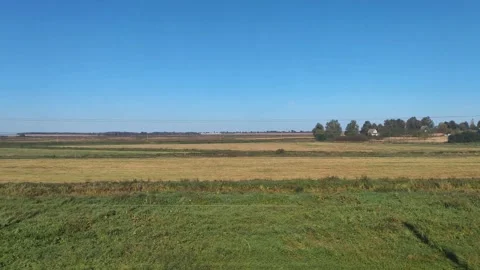 View from the train window of a beautiful landscape of fields and blue sky in Stock Footage 296579701