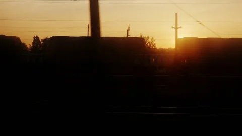 View from the train window at dawn. There are silhouettes of trees, station Stock Footage 76575328