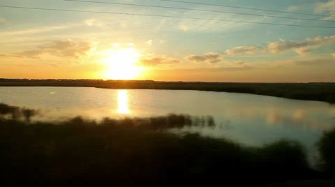 View from train window to field and lake at sunset Stock Footage