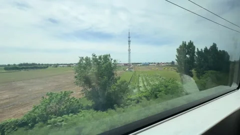 View from a train window looking at a green summer agriculture field Stock Footage 338100080