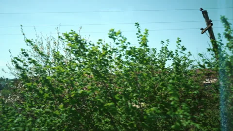 View from train window in motion - sun shines village through trees silhouette. Stock Footage 180073752