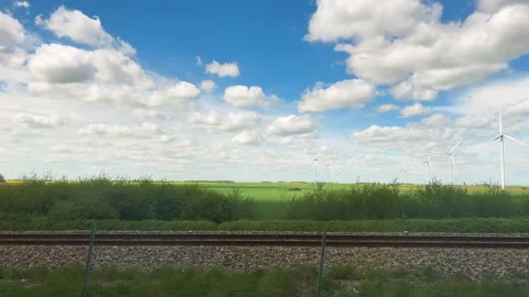 View from train window on picturesque fields, wind turbine and blue sky. 動画素材 311958351