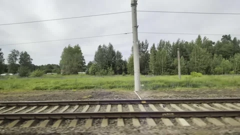 View from train window showing railway tracks, green landscape with lush trees Stock Footage 339866133