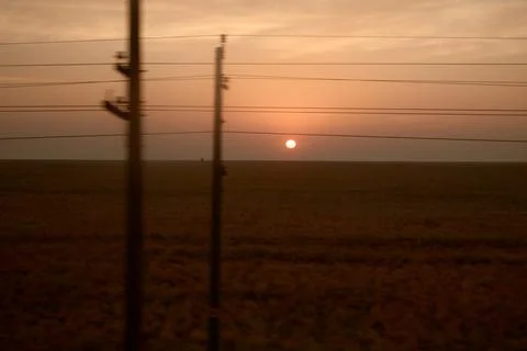 View from the train window. Sunrise in the steppe. Railway poles. Stock Photos