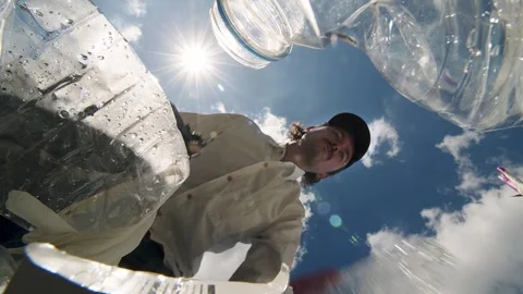 The view from the trash heap. POV: A man picks up trash against a blue sky with Stock Footage 247129642