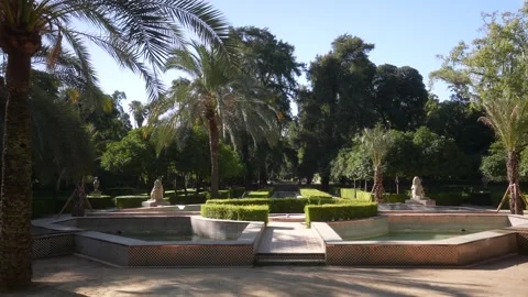 View of trees and fountain in Parque de Mari­a Luisa on a sunny day in Seville Vídeos de archivo 344542850