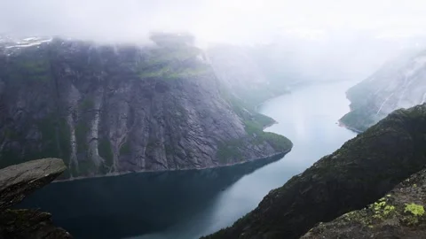 View from Trolltunga over blue Norwegian Fjord with tall surrounding mountains Stock Footage 252692716