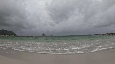 View of turquoise waves washing beach with Bleiksoya island under storm clouds Stock-Footage 343130561