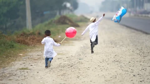 View of two boys running with balloons on a dirt road, Bangladesh. Video stock 334992021