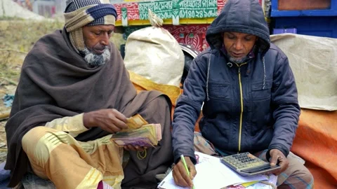 View of two men counting money and writing in a ledger, Bangladesh. Stockbeeldmateriaal 336427147