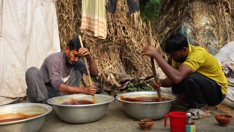 View of two men stirring jaggery in large bowls in Natore, Bangladesh. Vídeos de archivo 335651593