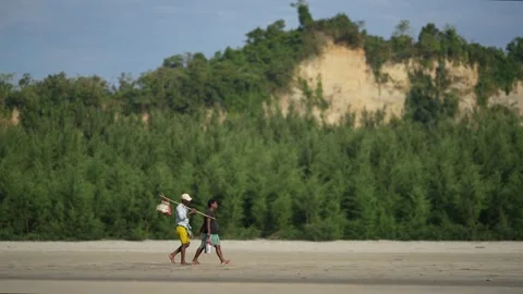 View of two men walking on the sandy beach in Cox's Bazar, Bangladesh. 스톡 동영상 335023439