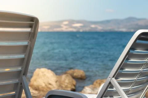 View of two white foldable benches near the sea, concept of vacation and summ Stock Photos