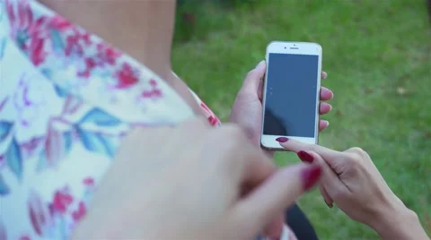 View of two women's hands using smartphonephone. Park background Stock Footage 67566736