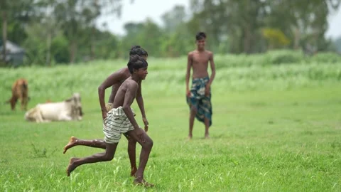 View of two young boys running through a green field, Bangladesh. Video stock 335584103