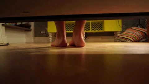 View from under the bed of a man treading on the wooden floor of a bedroom Stock Footage 170478756