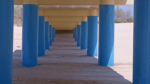 View under the bridge on sand beach, parallel blue columns hold bridge. Stock-Footage 114173899