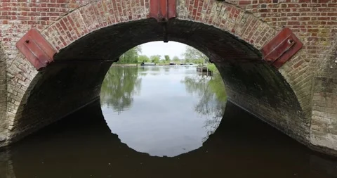 View from under a dark brick bridge arch looking out onto the river, showing ref Stock Footage 308418520