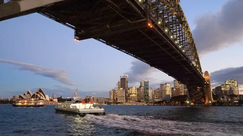 View under the Harbour Bridge and city skyline with ferries in the evening Stock Footage 103461334