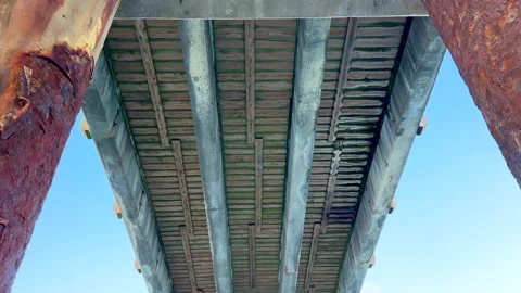 View Under Ocean Pier With Barnacles and Rust Extending Toward Sea Vídeo Stock 337740725