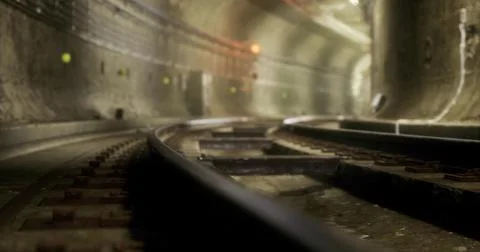 View of underground rail tracks in a dimly lit tunnel with a sense of stillne Illustrazione stock