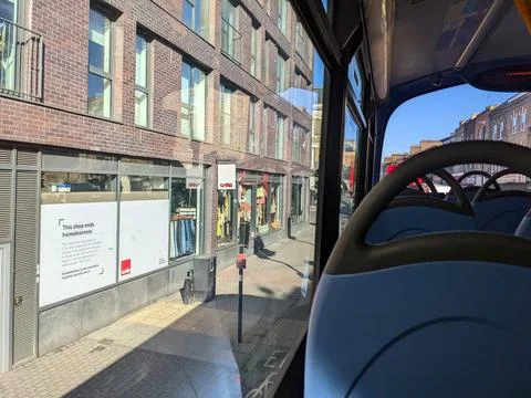 View from the upper floor of a double-decker bus with empty seats facing shops Stock Photos